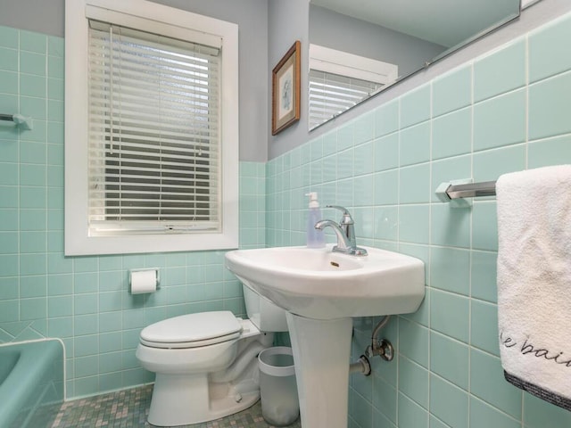 bathroom with a tub to relax in, toilet, tile walls, and tile patterned flooring