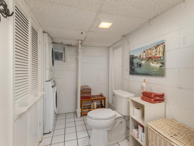 bathroom featuring tile patterned floors, toilet, and stacked washing maching and dryer