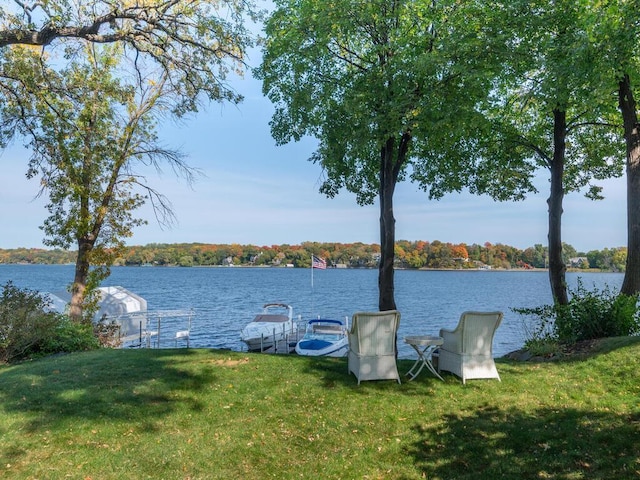 view of dock with a lawn and a water view