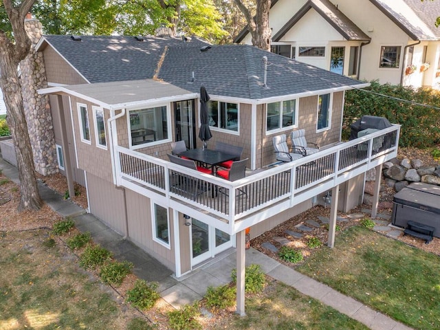 rear view of property featuring roof with shingles, a deck, and a chimney