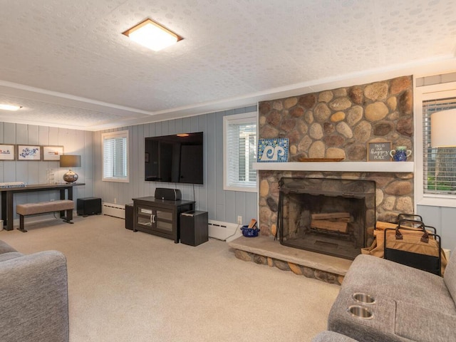 carpeted living area featuring a baseboard radiator, a textured ceiling, and a stone fireplace