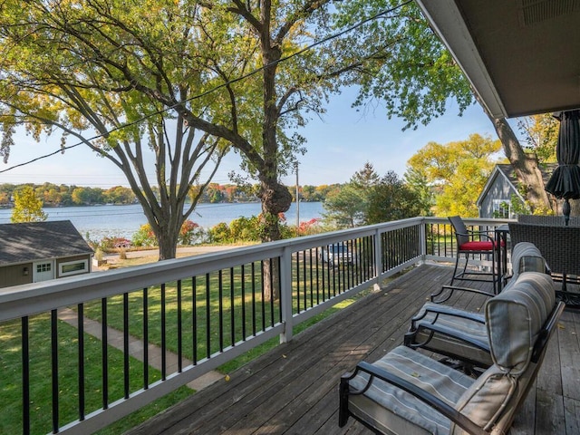 wooden terrace featuring a water view and a lawn