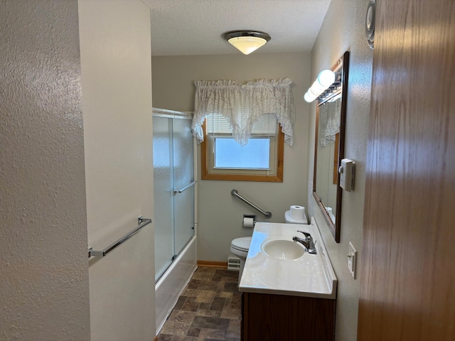 bathroom featuring baseboards, toilet, vanity, stone finish floor, and a textured ceiling