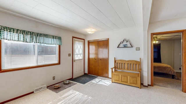 foyer entrance with visible vents, light carpet, and baseboards