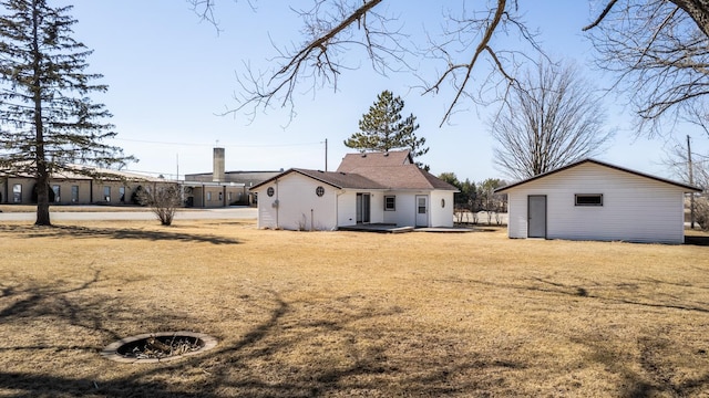 rear view of property with a lawn and an outdoor structure