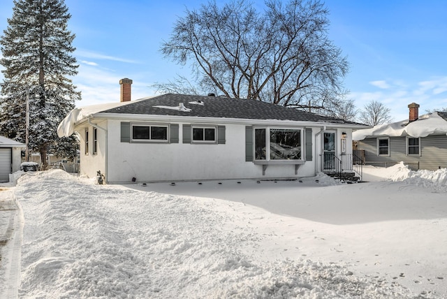 view of front of property with stucco siding, a chimney, and a shingled roof