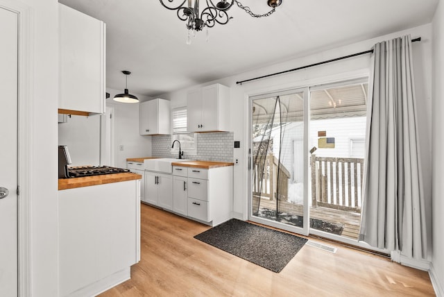 kitchen with visible vents, a sink, wood counters, white cabinetry, and light wood-style floors