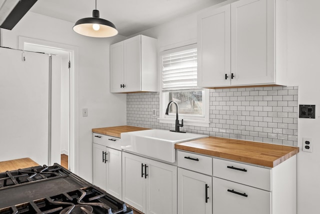 kitchen featuring a sink, white cabinets, tasteful backsplash, and butcher block counters