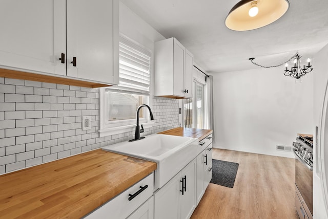 kitchen featuring a sink, white cabinets, light wood-type flooring, and wood counters