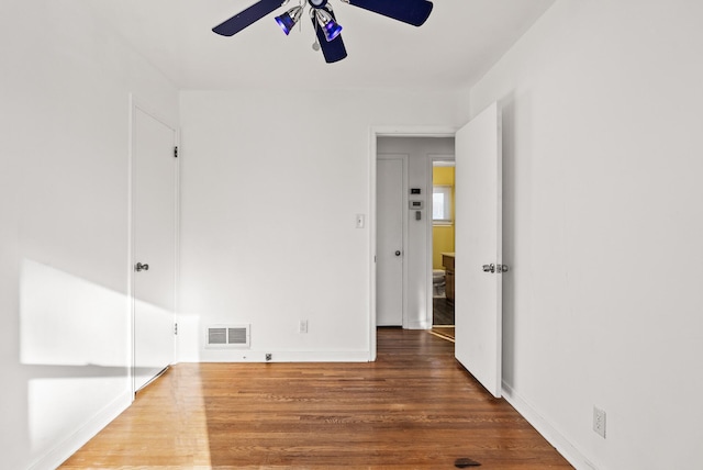 empty room featuring visible vents, baseboards, wood finished floors, and a ceiling fan