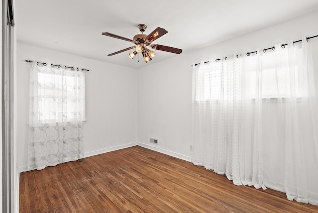 spare room featuring ceiling fan, wood finished floors, visible vents, and a healthy amount of sunlight