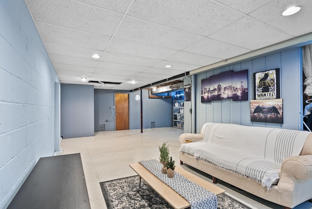 living area featuring concrete block wall, recessed lighting, and a drop ceiling