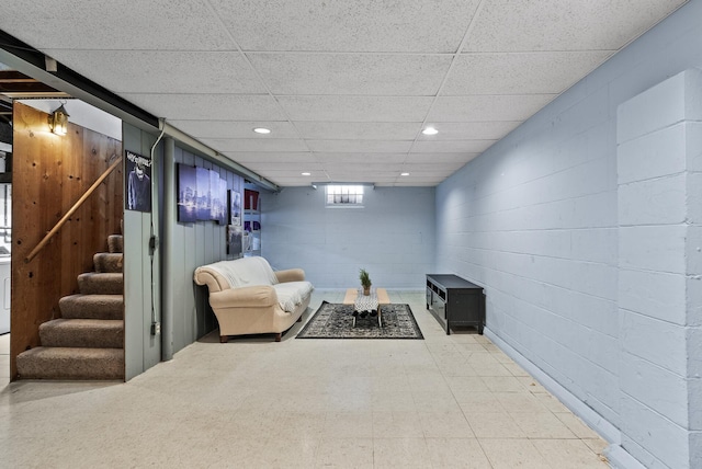 living area featuring stairway, concrete block wall, recessed lighting, and a paneled ceiling