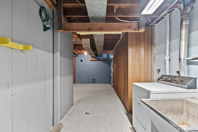 washroom featuring a sink, washer / clothes dryer, wood walls, light floors, and laundry area