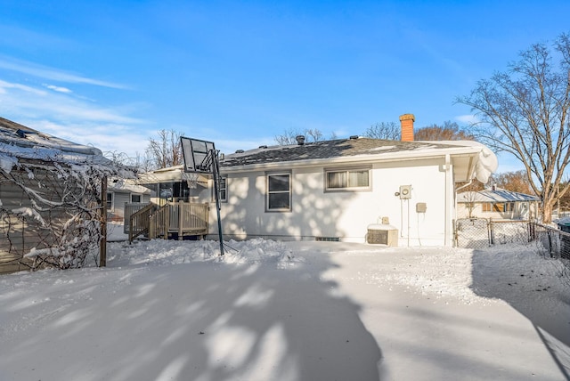 snow covered property featuring a chimney and fence