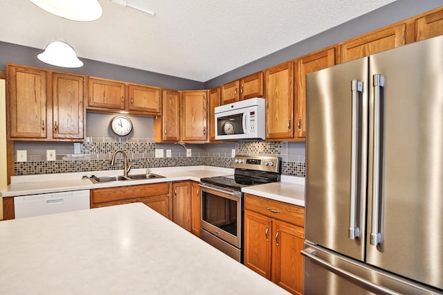 kitchen featuring backsplash, light countertops, hanging light fixtures, stainless steel appliances, and a sink