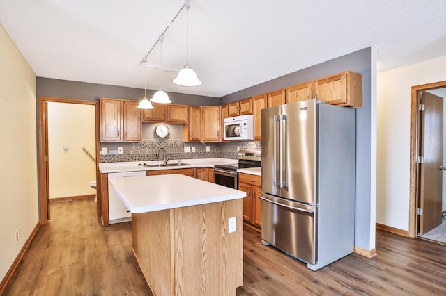 kitchen featuring a sink, backsplash, wood finished floors, appliances with stainless steel finishes, and light countertops