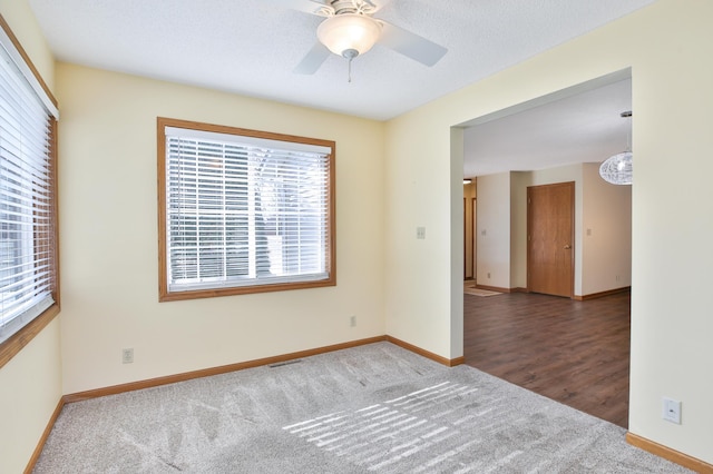 carpeted empty room with baseboards, a textured ceiling, and ceiling fan