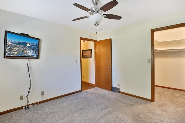 unfurnished bedroom with a ceiling fan, baseboards, carpet floors, a spacious closet, and a closet