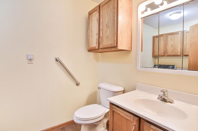 half bathroom with baseboards, toilet, wood finished floors, and vanity