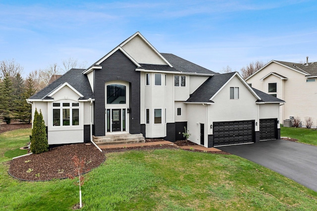 view of front of house featuring aphalt driveway, a front lawn, roof with shingles, and stucco siding