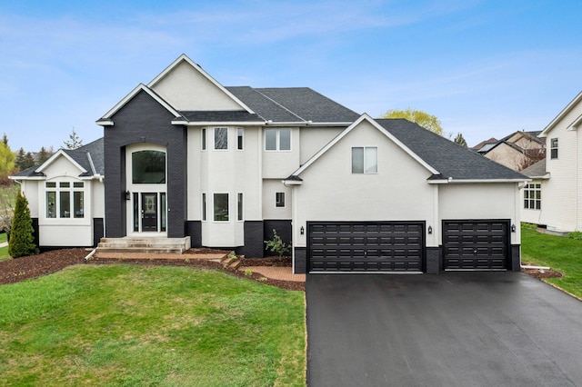 view of front of house with roof with shingles, an attached garage, a front yard, and aphalt driveway