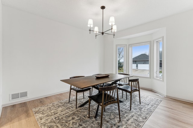 dining room with baseboards, visible vents, an inviting chandelier, and light wood-type flooring