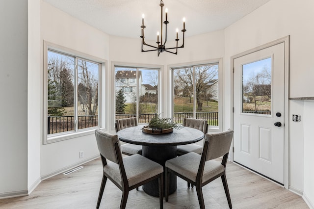 dining room featuring light wood-type flooring, a notable chandelier, and a wealth of natural light