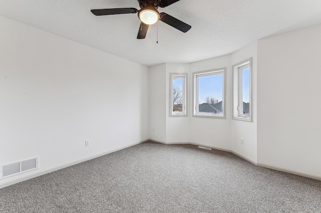 carpeted empty room with a ceiling fan, baseboards, visible vents, and a textured ceiling