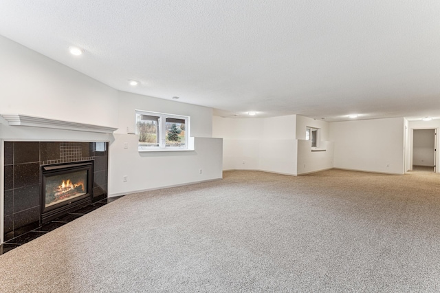 unfurnished living room featuring recessed lighting, a textured ceiling, a tiled fireplace, and carpet