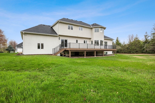 rear view of house featuring a lawn, a deck, a shingled roof, and stucco siding