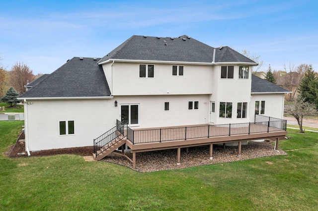 rear view of property featuring a lawn, a wooden deck, a shingled roof, and stucco siding