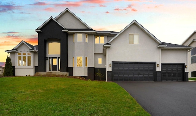 view of front of property featuring an attached garage, stucco siding, a yard, and driveway