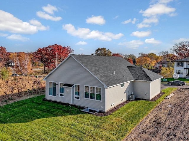 back of property with a lawn, a shingled roof, and central AC