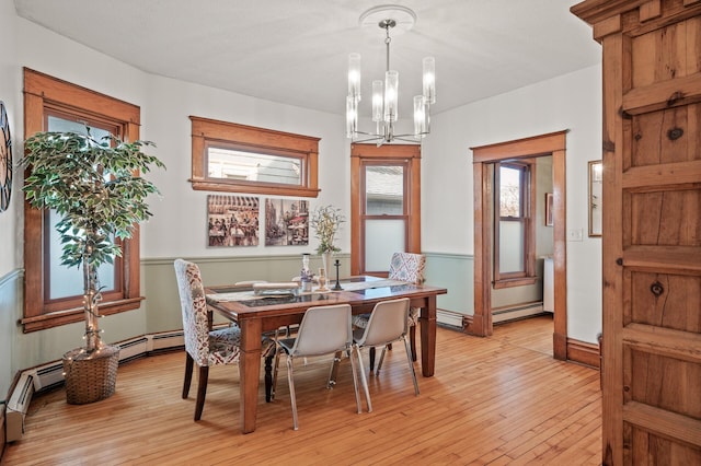 dining room featuring light wood-type flooring, a notable chandelier, and a baseboard radiator