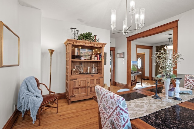 living room featuring a notable chandelier, light wood-style floors, and baseboards