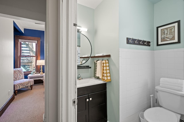 half bathroom with toilet, tile walls, ensuite bath, and vanity