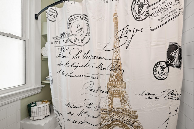 bathroom featuring curtained shower and tile walls