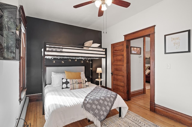 bedroom featuring baseboards, baseboard heating, a ceiling fan, and hardwood / wood-style flooring