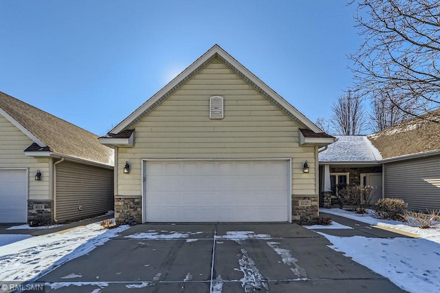 view of front of home featuring a garage, stone siding, and driveway