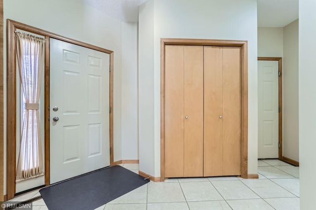 entryway with light tile patterned floors, a healthy amount of sunlight, and baseboards