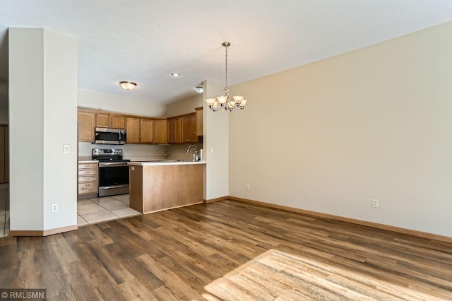 kitchen featuring wood finished floors, light countertops, appliances with stainless steel finishes, open floor plan, and a chandelier