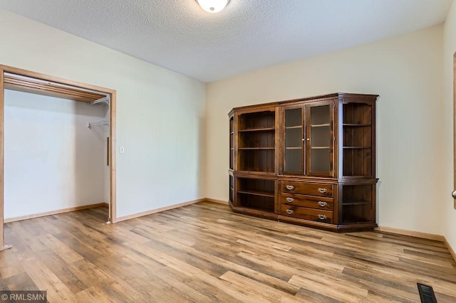 unfurnished bedroom with visible vents, light wood finished floors, and a textured ceiling