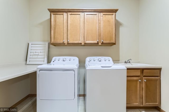 clothes washing area with a sink, cabinet space, and separate washer and dryer