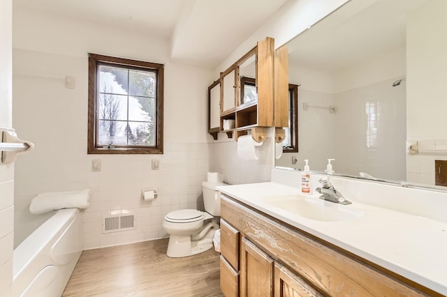 bathroom with vanity, wood finished floors, visible vents, tile walls, and toilet