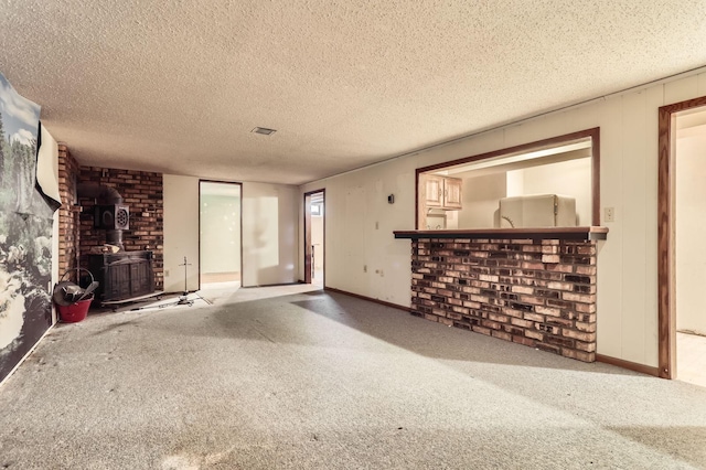 unfurnished living room with carpet floors, a textured ceiling, and a wood stove