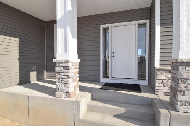 view of exterior entry with stone siding and a porch