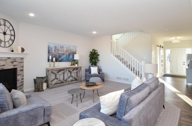 living room featuring visible vents, recessed lighting, a stone fireplace, and stairs