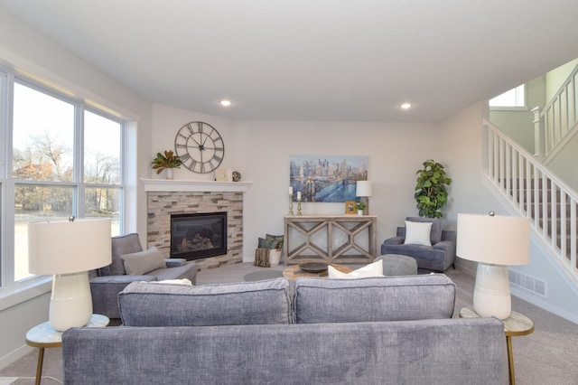 living area with visible vents, baseboards, stairs, carpet flooring, and a glass covered fireplace