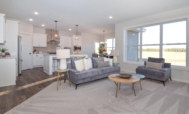 living area with recessed lighting, baseboards, an inviting chandelier, and dark wood-style floors